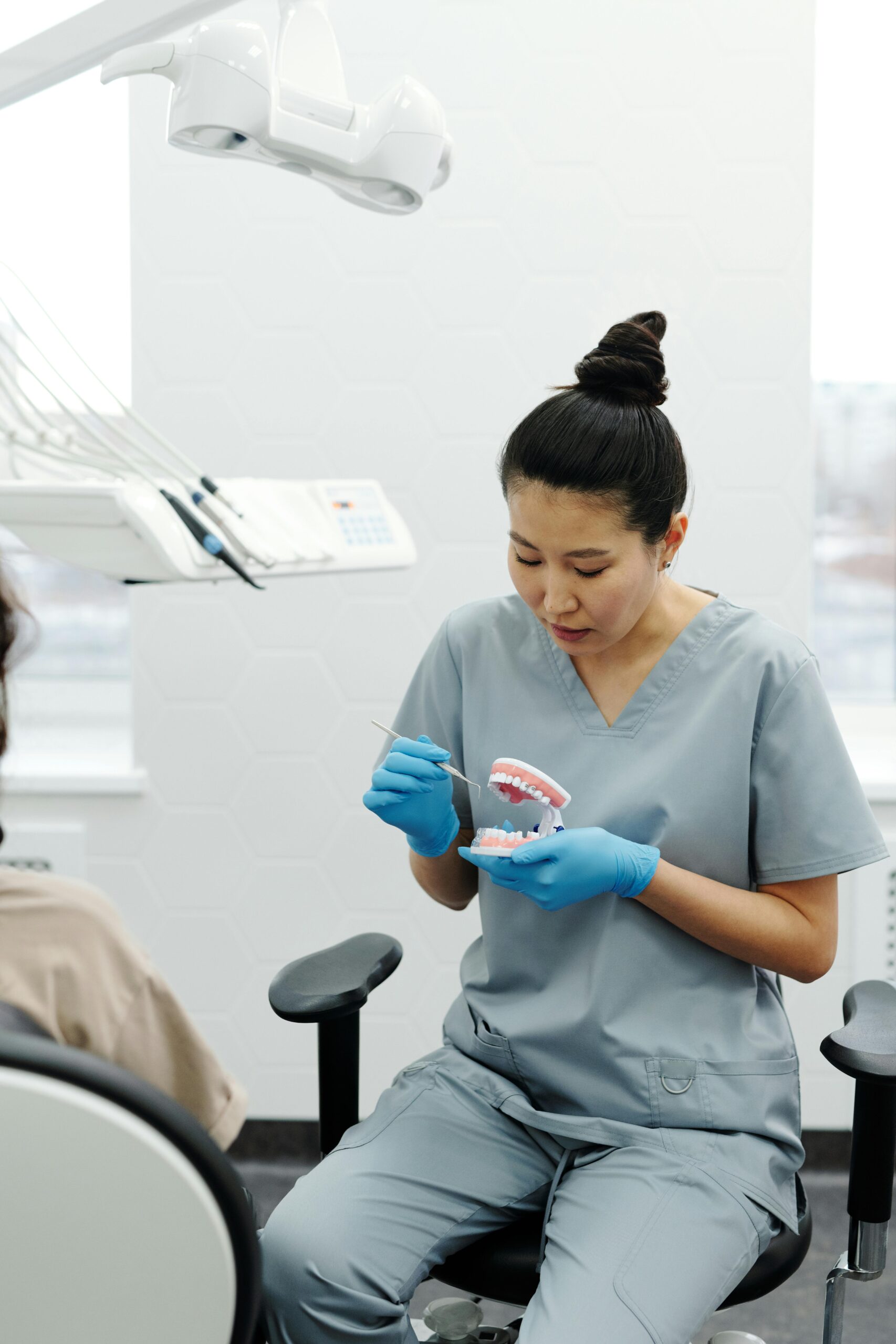 Professional dentist instructs a patient on dental care using a denture model in a modern clinic.